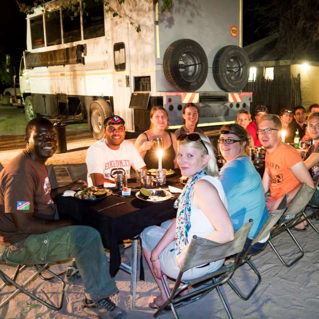 Overland safari groupo eating candle light dinner